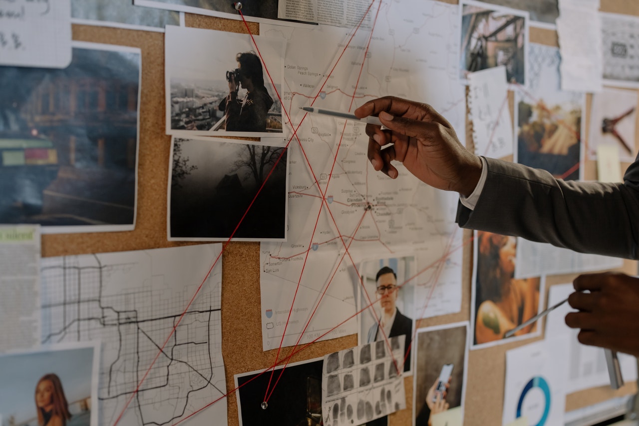 Cork board with clues and strings connecting pins